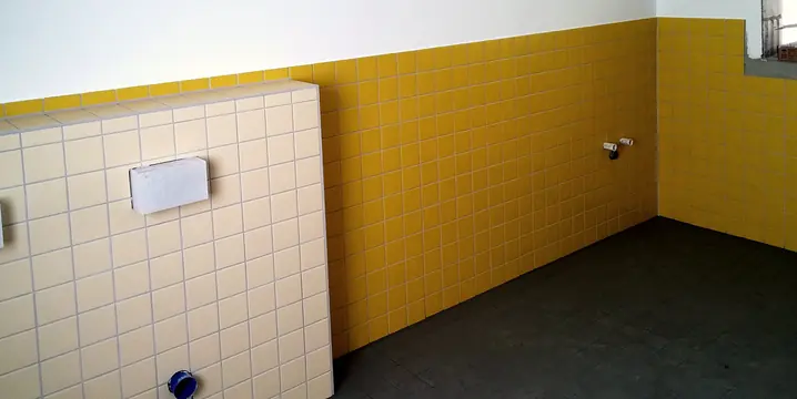 Gelbe Wandfliesen und helle Vorwand mit WC-Anschluss