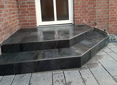 Geflieste Eingangsstufen vor einer Klinkerwand